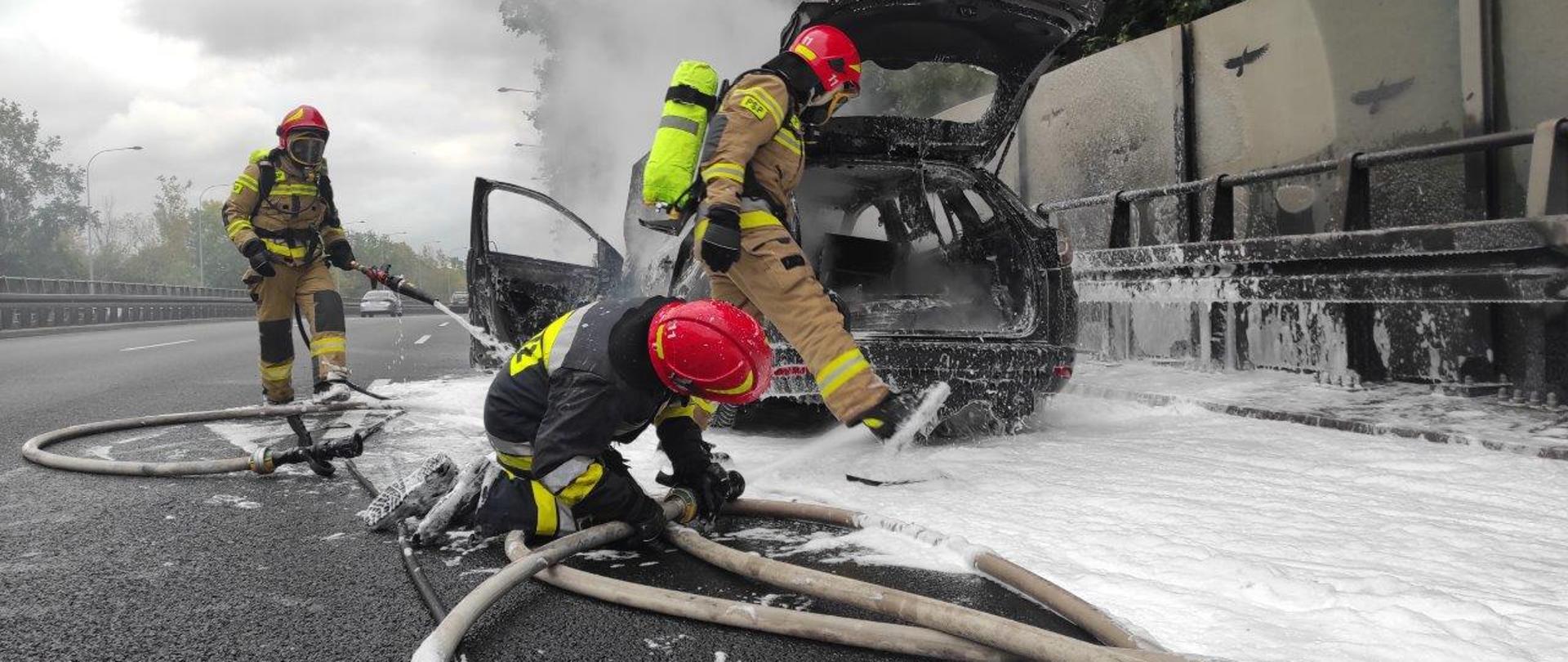 Strażacy podczas gaszenia pożaru samochodu.