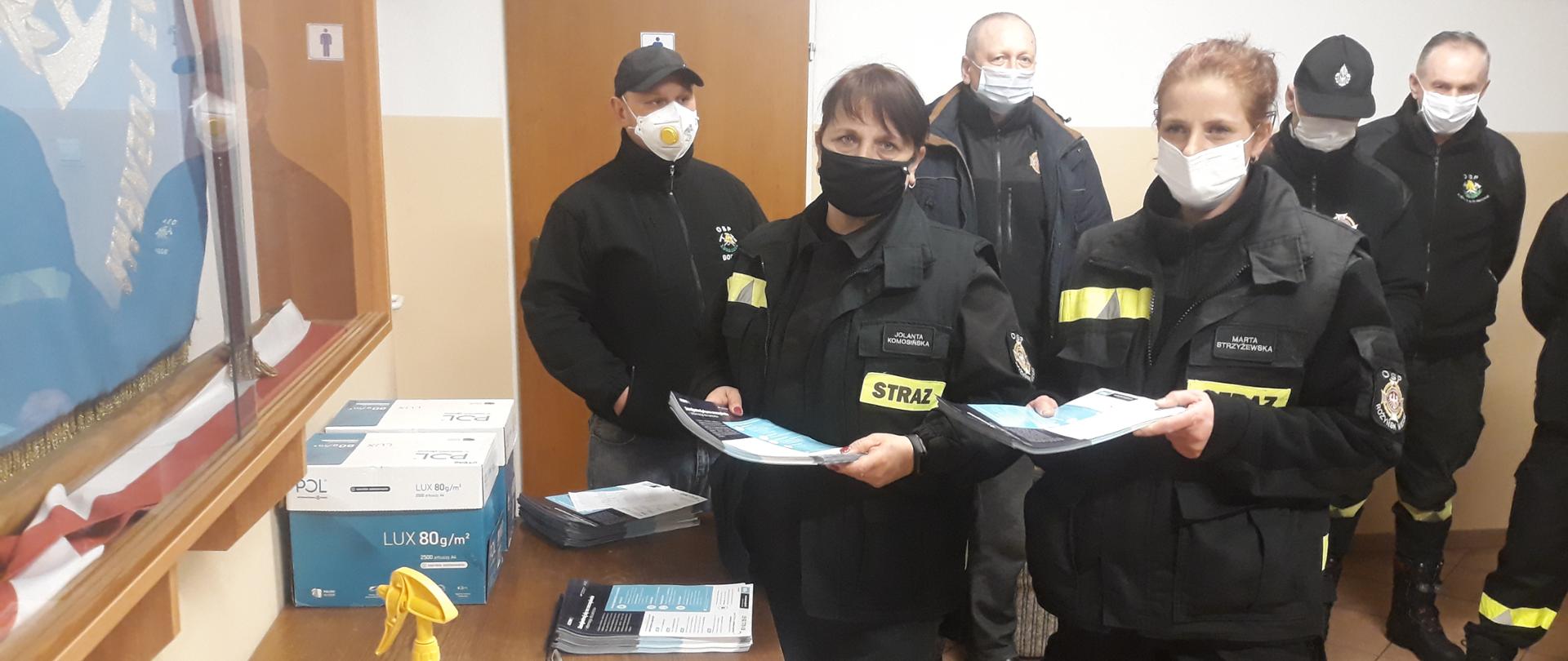 Druhny i druhowie rozkładają ulotki na stole dzieląc je według miejscowości.