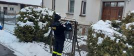 Strażak wrzuca ulotkę do skrzynki na listy przed posesją