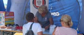 Na zdjęciu widać osoby w punkcie informacyjnym PSSE w Gdyni zlokalizowanym na plaży w Gdyni