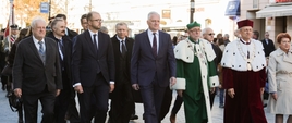 ministrowie i rektorzy idą po ulicy, za nimi reszta pochodu