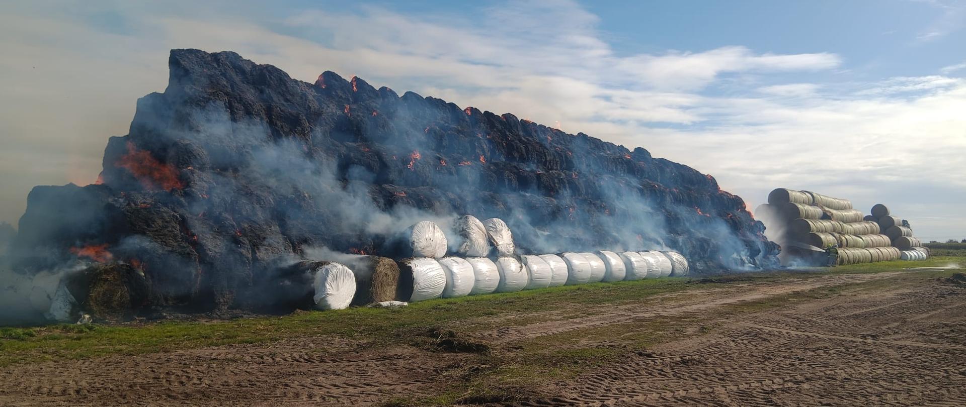 Pali się stóg na polu, widać ogień, po prawej jest kolejny stóg