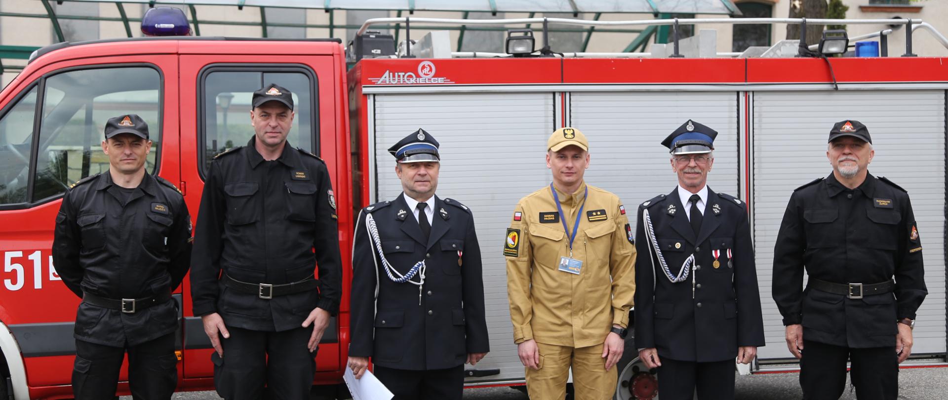 Grupowe zdjęcie Zastępcy Komendanta Centralnej Szkoły PSP w towarzystwie dwóch druhów OSP Chorzenice-Witkowice oraz Naczelnika Wydziału Technicznego Centralnej Szkoły PSP jego Zastępcy oraz Naczelnika Wydziału Kwatermistrzowskiego na tle przekazywanego samochodu specjalnego Iveco Daily GLBA 1/1