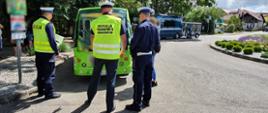 Inspektor ITD i funkcjonariusze Policji kontrolują wolnobieżny pojazd turystyczny w Ustroniu Morskim. W tle stoi oznakowany radiowóz ITD.