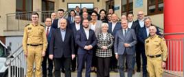 Kilkanaście osób stoi na schodach przed budynkiem i się uśmiecha 