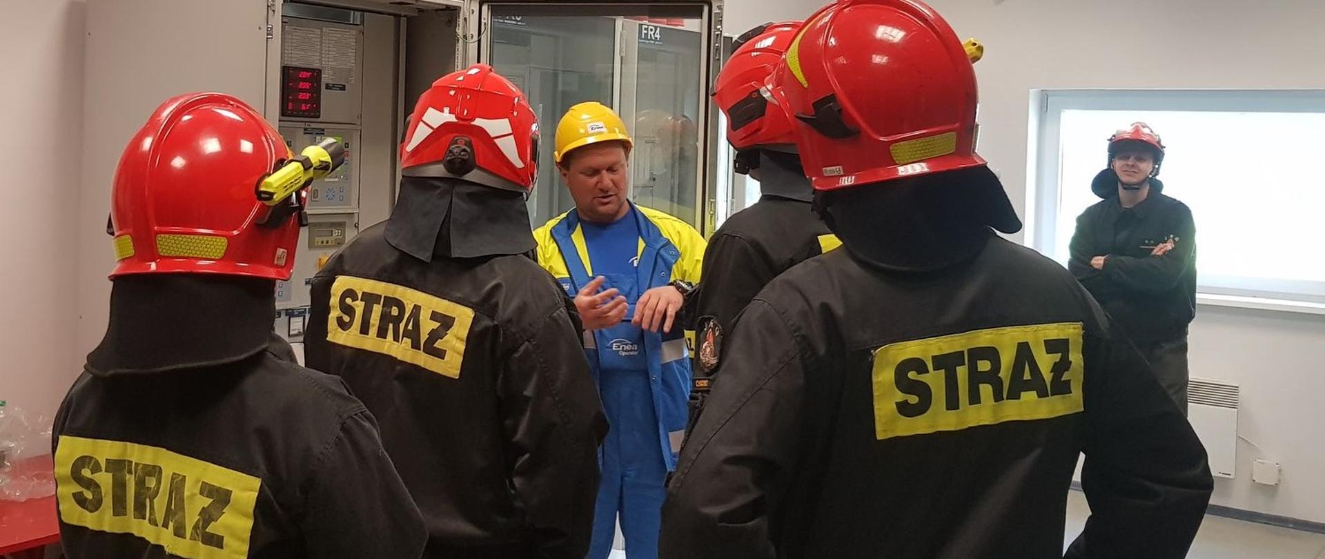 Zdjęcie przedstawia strażaków podczas rozpoznania operacyjnego stacji elektroenergetycznej w ramach doskonalenia zawodowego.
W tle obiekty stacji elektroenergetycznej.
