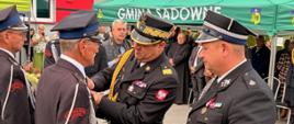 „Moment wręczania medali i odznaczeń zasłużonym druhom OSP. Komendant Wojewódzki PSP nadbryg. Artur Gonera przypina medal do munduru strażaka-ochotnika.”