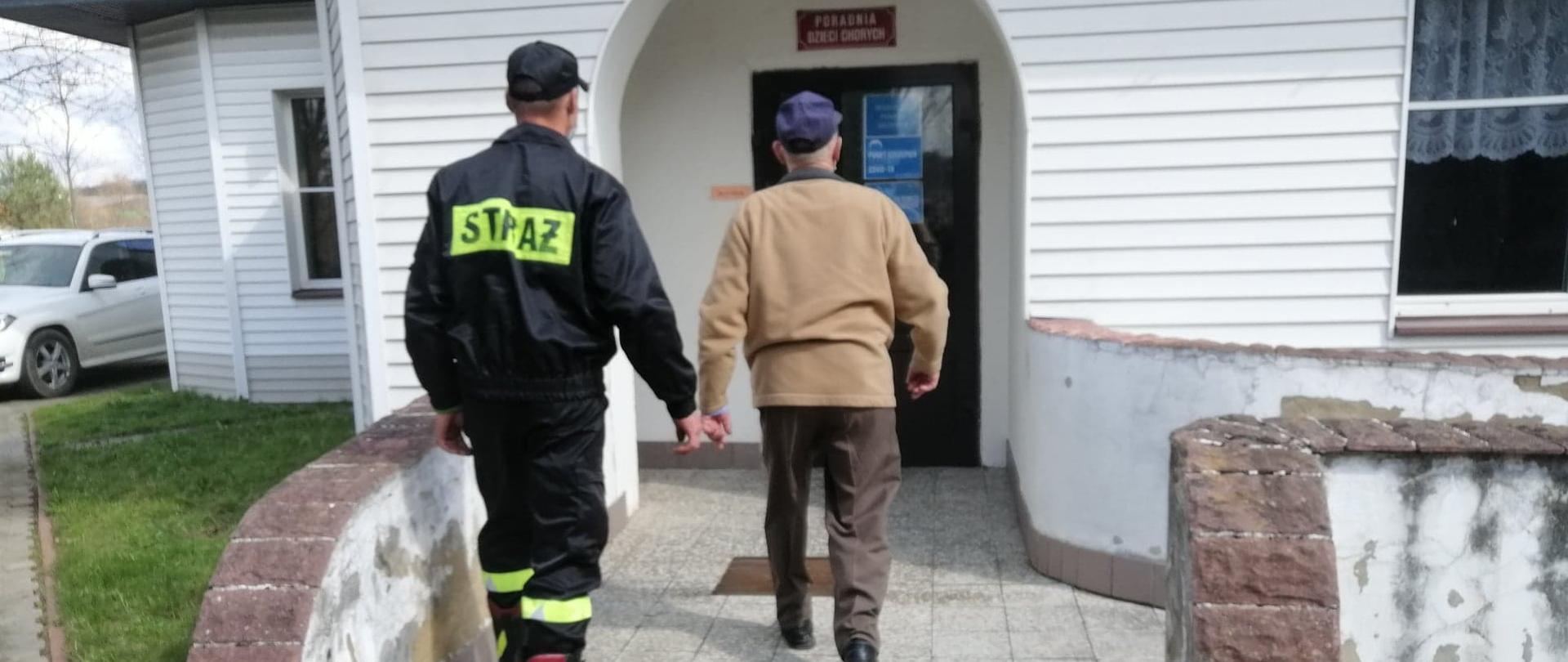 Ratownik OSP odprowadzający osobę do punktu szczepień.