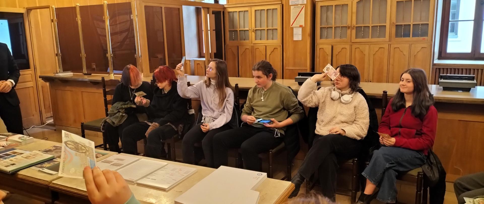 zdjęcie, przedstawia uczniów naszej szkoły siedzących w rzędzie na prelekcji w banku