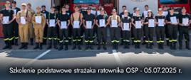 Zdjęcie przedstawia uczestników kursu podstawowego z dyplomami ukończenia przed garażami JRG Ustrzyki Dolne