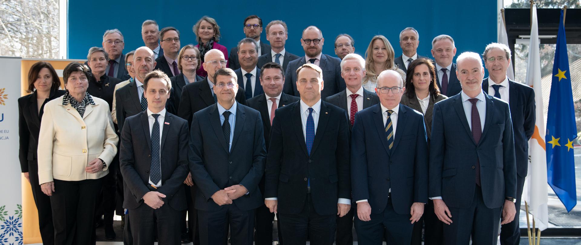 About thirty government and institutional representatives stand in several rows for a group photo during a meeting, with the flags of Poland and the European Union on the right.