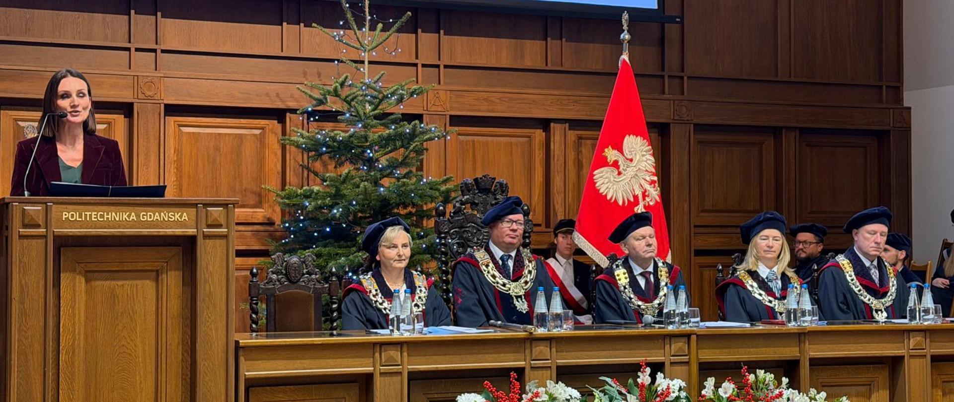 wojewoda stoi za pulpitem i przemawia w auli politechniki gdańskiej 