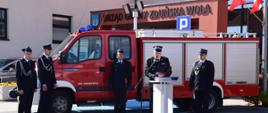 Na zdjęciu widoczny jest samochód ratowniczo gaśniczy z modułem do ratownictwa technicznego Renault Mascot z OSP Janiszewice oraz strażacy. Przy mównicy jest Łódzki Komendant Wojewódzki. 