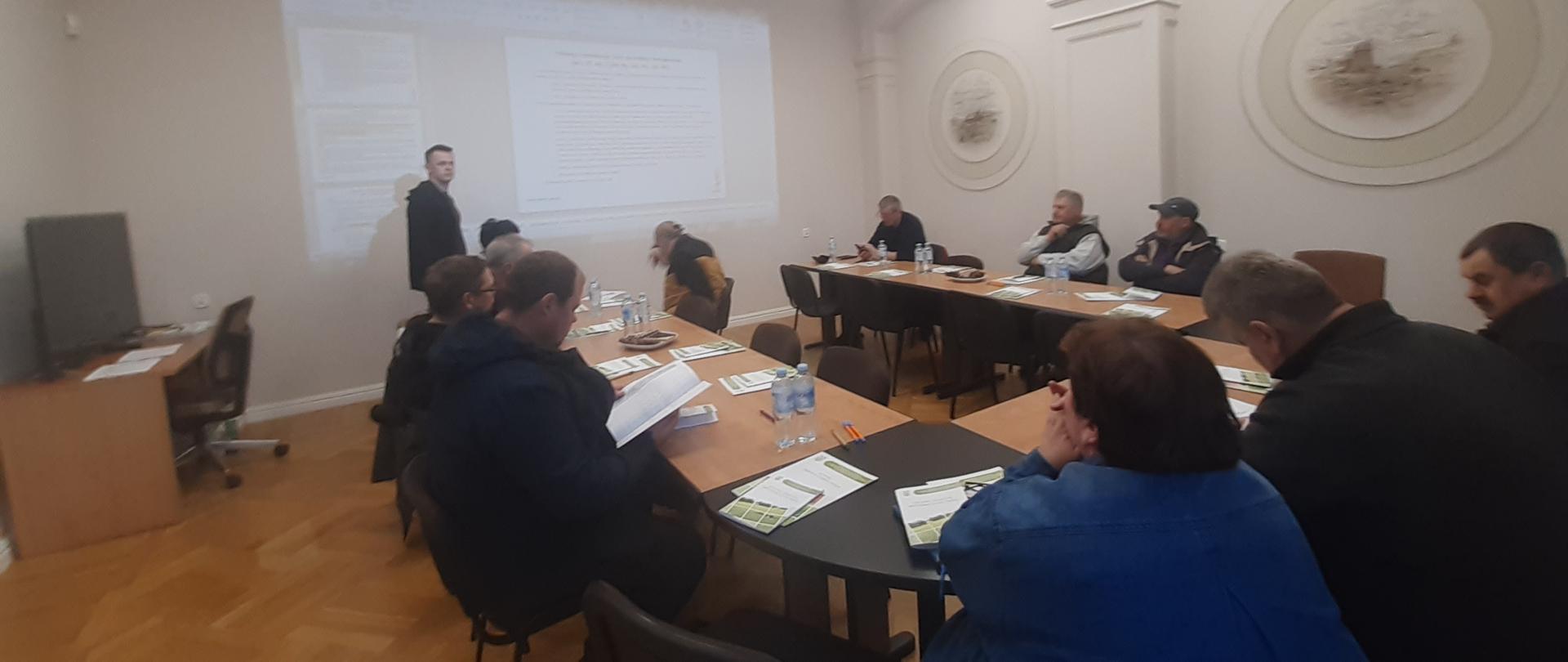 Uczestnicy szkolenia siedzą na sali konferencyjnej. Inspektor stoi przodem do słuchaczy i prowadzi wykład