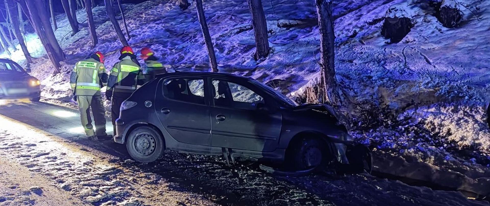 Rozbity samochód osobowy a obok strażacy