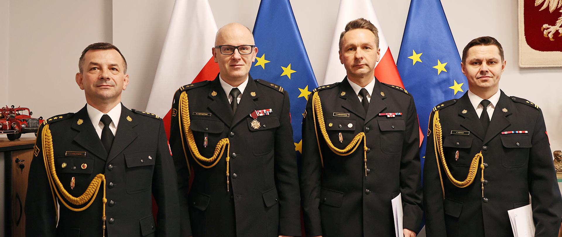 Wspólna fotografia czterech oficerów PSP, w tle flagi RP i UE.