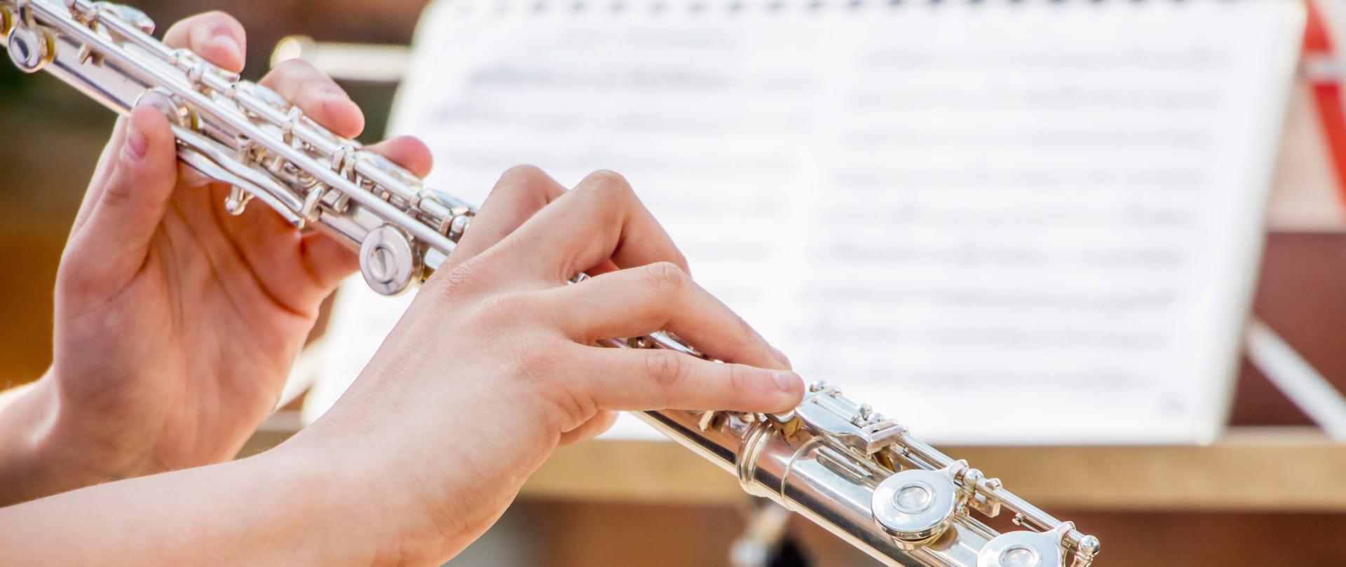 Zdjęcie przedstawia dziewczynkę grającą na flecie