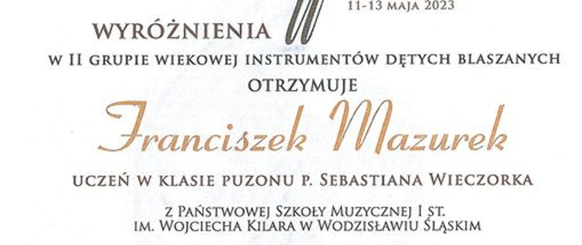Dyplom z napisem "Dyplom wyróżnienia w II grupie wiekowej instrumentów dętych blaszanych otrzymuje Franciszek Mazurek Uczeń w klasie puzonu p. Sebastiana Wieczorka"