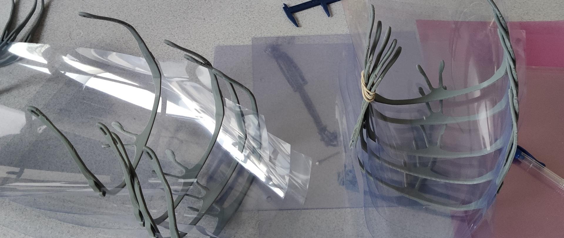 Elementy masek leżą na stole obok komputera.