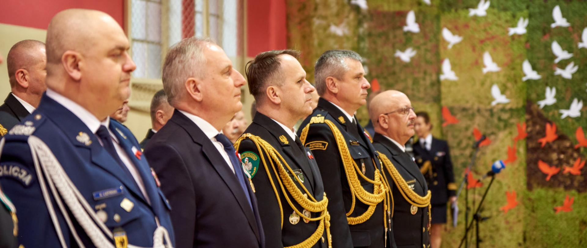 Zaproszeni goście stoją obok siebie podczas uroczystości.