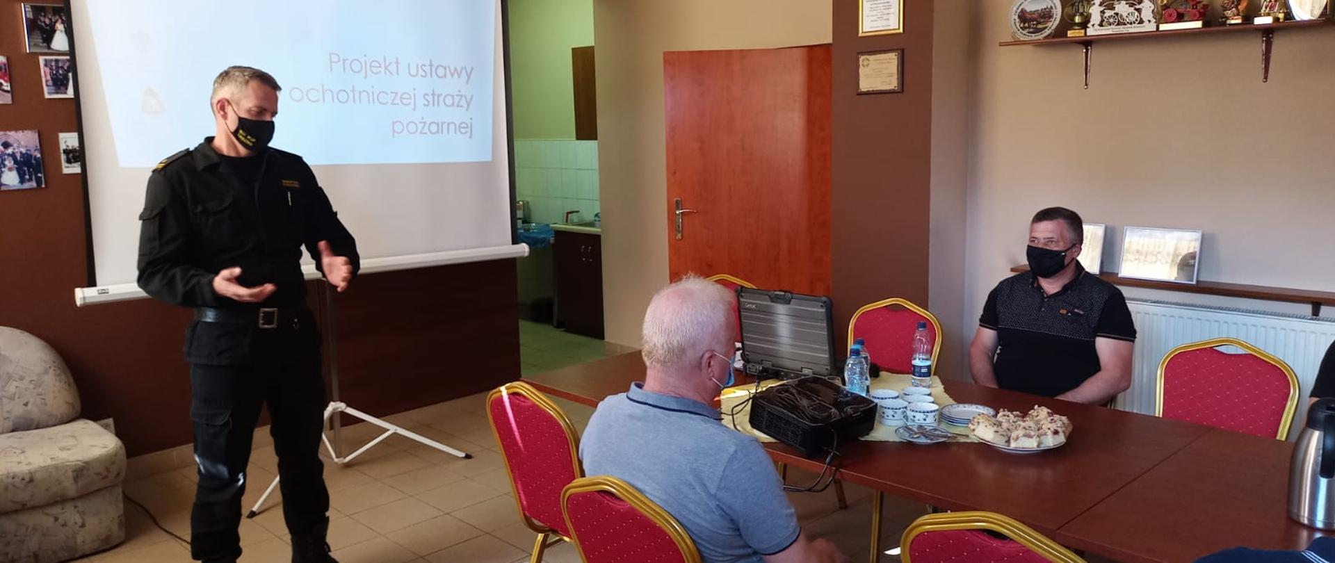 Strażak omawia prezentacje z druhami OSP.