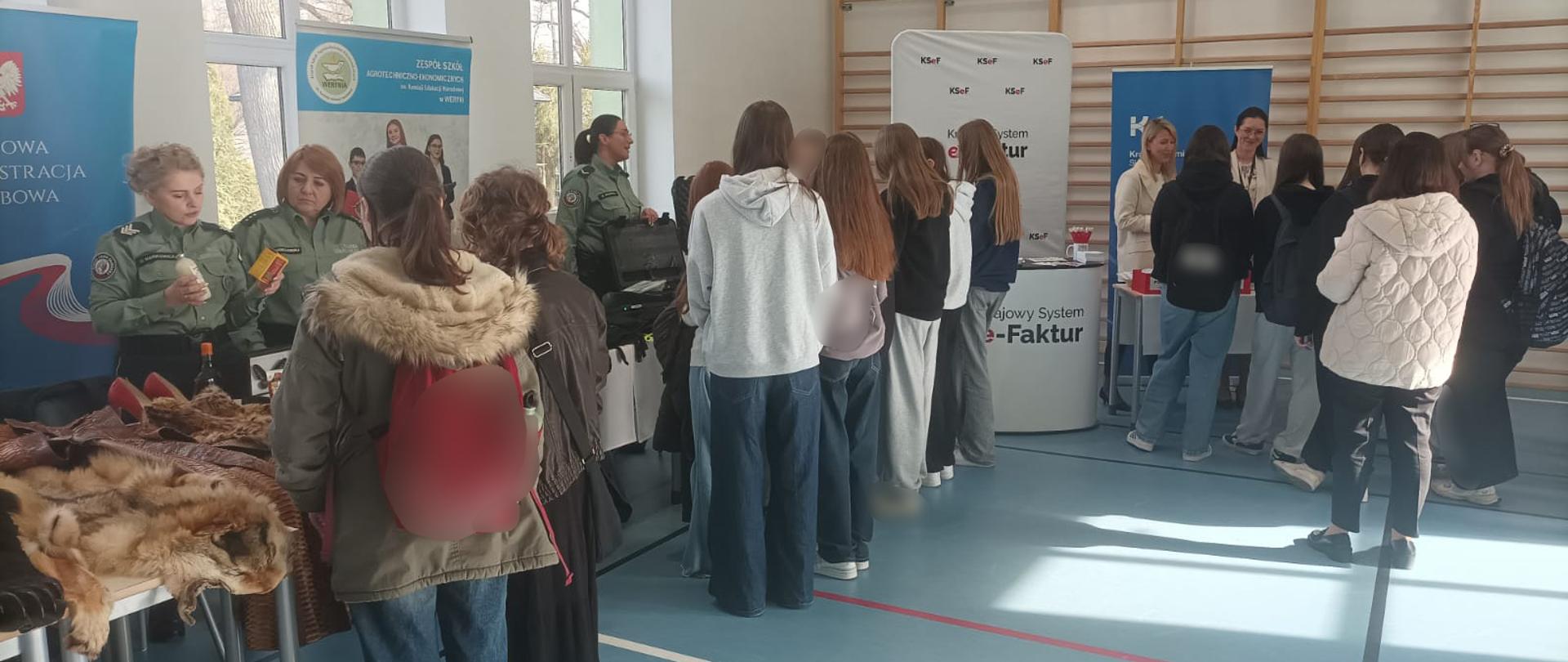 Uczniowie stoją przy stanowisku podkarpackiej KAS, przy którym są funkcjonariuszki SCS i ekspertki z US.