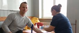 Pielęgniarka pobiera do badania krew, siedzącemu na krześle mężczyźnie 