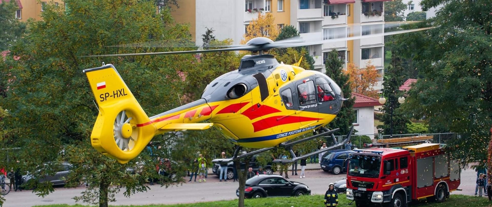 Śmigłowiec Lotniczego Pogotowia Ratunkowego w trakcie lądowania, teren zabezpieczony przez strażaków