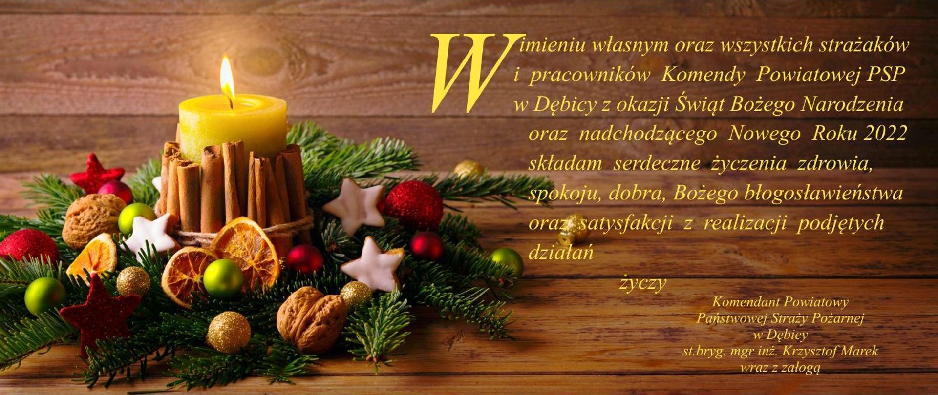 życzenia na Boże Narodzenie 2021 na ciemnym tle, stroik z zielonych gałązek i paląca się żółta świeca