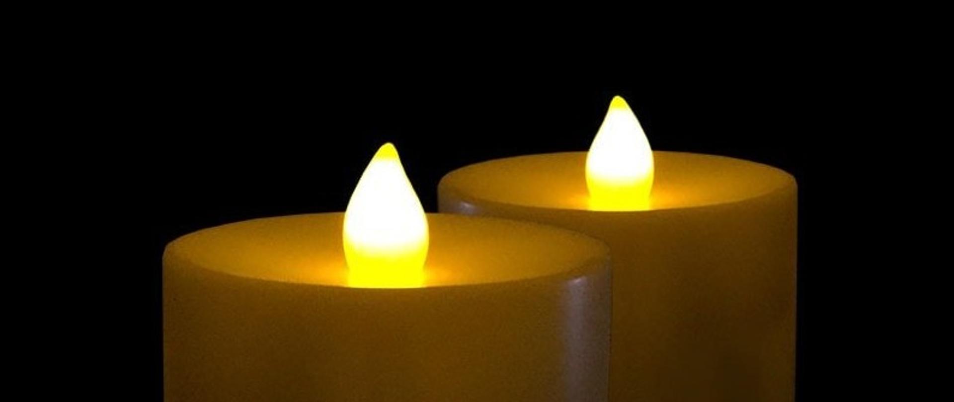 zdjęcie , dwie palące się świeczki na czarnym tle