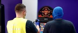 Dwóch funkcjonariuszy podczas sprawdzania automatu do gier.