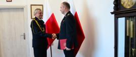 Pomorski komendant wojewódzki Państwowej Straży Pożarnej wręcza akt powołania na stanowisko komendanta powiatowego Państwowej Straży Pożarnej strażakowi gratulując mu.