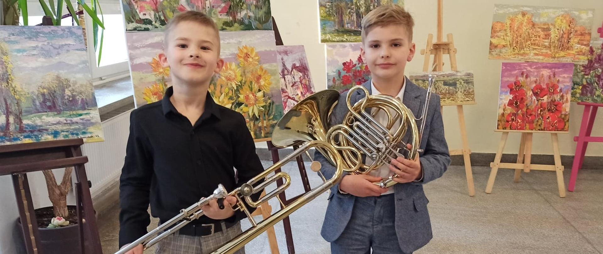 Sylwetki Alexa i Tymona na tle wystawy w holu ZSM w Krośnie