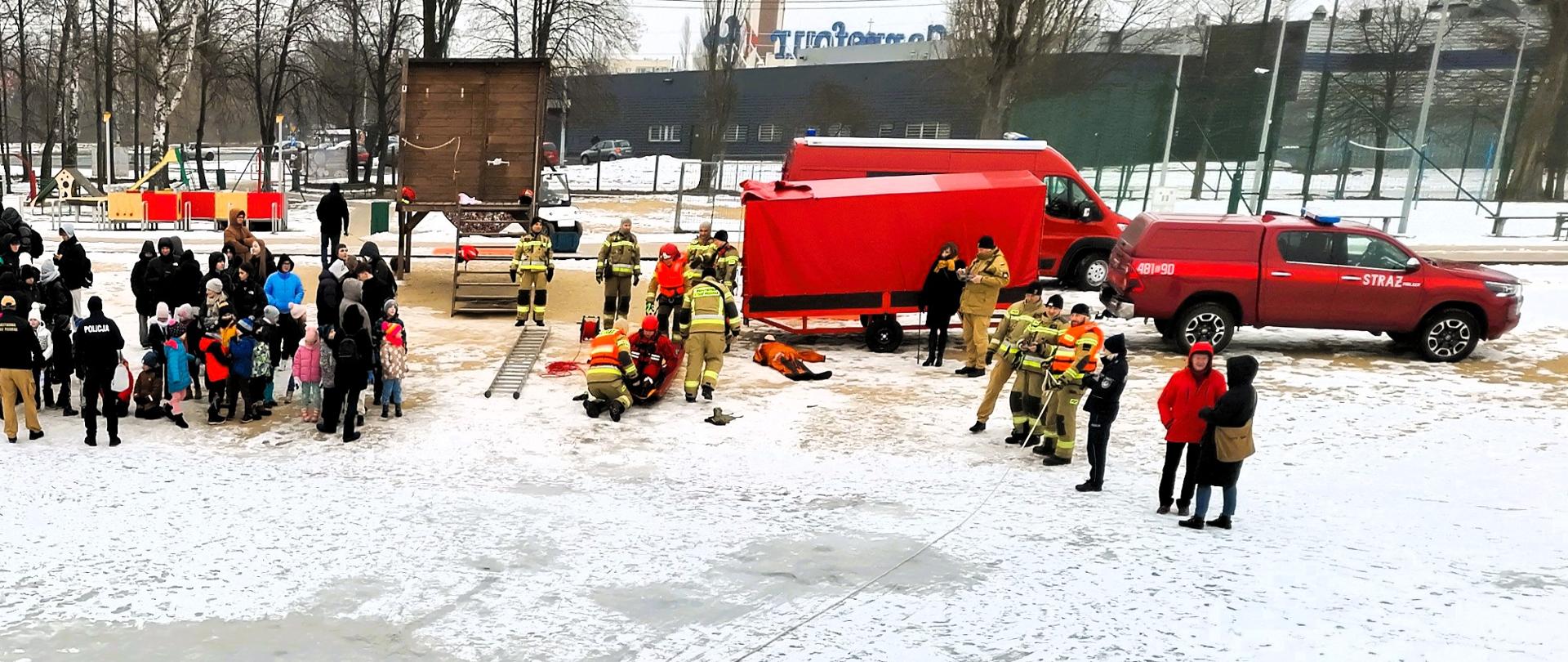 Zdjęcie wykonane podczas akcji "Bezpieczne Ferie 2026". Na zdjęciu młodzież przyglądająca się pokazom ratownictwa lodowego. Pokazy realizowane przez strażaków KP PSP w Pabianicach.