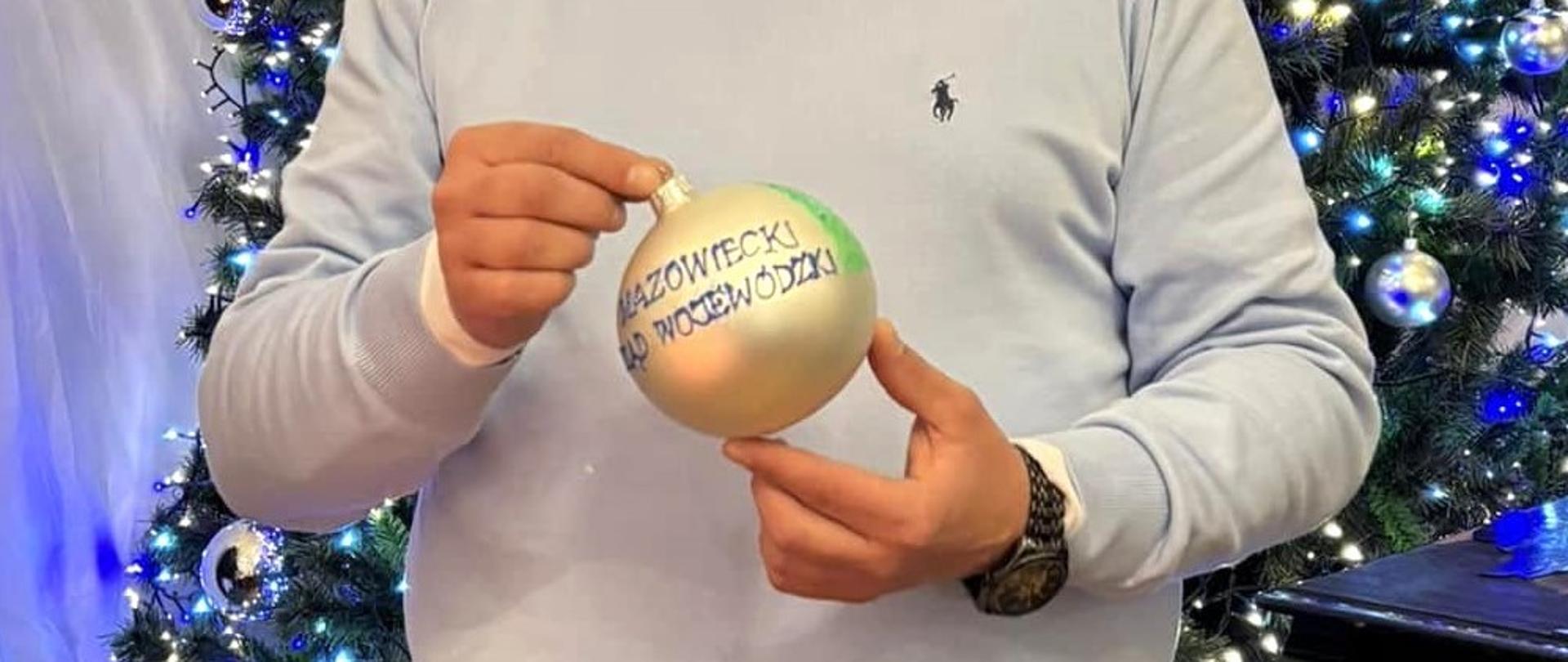 Kierownik Delegatury Mazowieckiego Urzędu Wojewódzkiego w Radomiu Rafał Molga z pomalowaną przez siebie bombką w ramach akcji charytatywnej