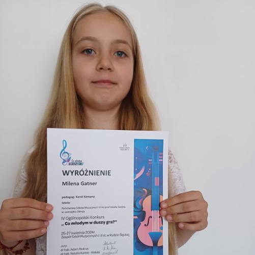 Osiem dziewczynek stoi w rzędzie trzymając dyplomy, za nimi stoi kobieta i dwóch mężczyzn.