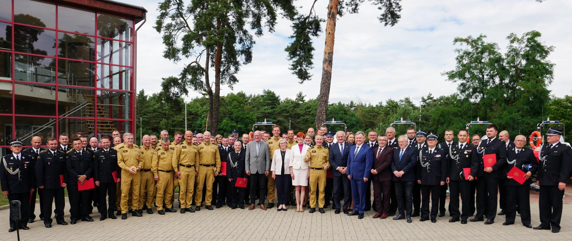 wspólne zdjęcie strażaków i zaproszonych gości przed budynkiem jednostki