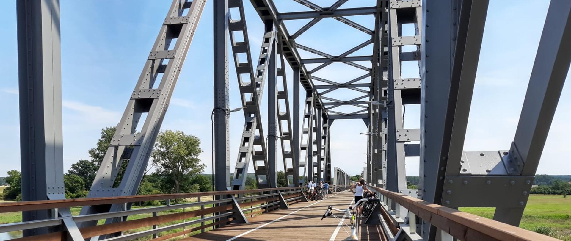 Konstrukcja stalowa mostu kolejowego z perspektywy osoby stojącej na moście.