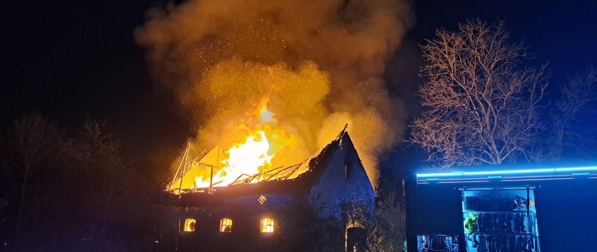 Zdjęcie przedstawia obiekt gospodarczy w całości objęty ogniem. Widoczny jest słup ognia wydobywający się z wnętrza budynku. Dach zawalił się do środka