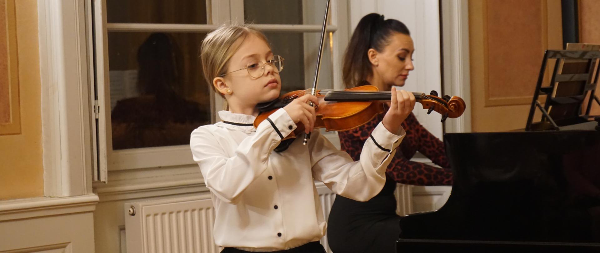 Na Sali Balowej wejherowskiego Muzeum gra na skrzypcach uczennica Szkoły Muzycznej. W tle przy fortepianie Urszula Zakrzewska akompaniuje uczennicy.