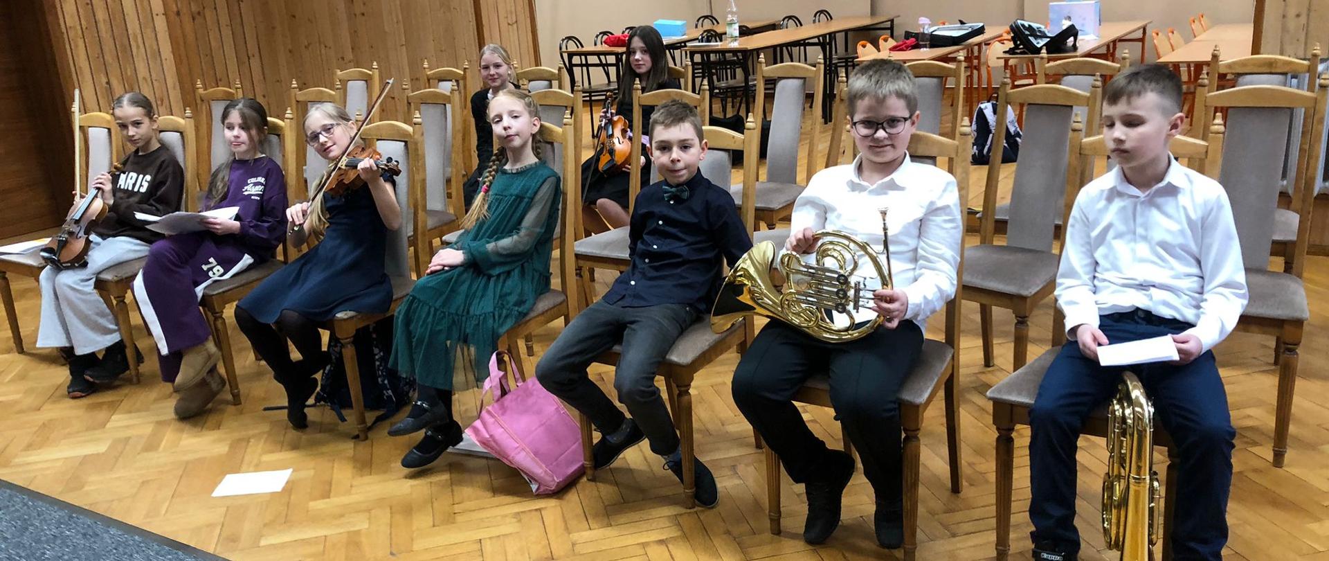 Wykonawcy i publiczność siedzący na widowni.