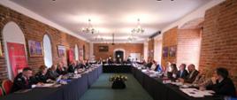 Uczestnicy 24. Posiedzenia Dyrektorów Generalnych Ochrony Ludności Rady Państw Morza Bałtyckiego siedzą przy stołach ustawionych w sali konferencyjnej.