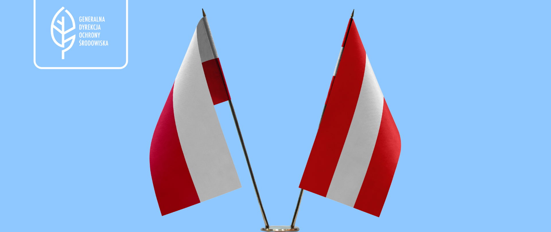 Na niebieskim na stojaku postawione są dwie flagi: Polski i Danii (obie w kolorach białym i czerwonym).
W lewym górnym rogu logotyp Generalnej Dyrekcji Ochrony Środowiska (biały liść).