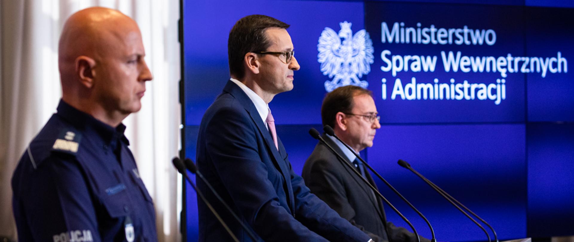 Od lewej: Jarosław Szymczyk, Mateusz Morawiecki, Mariusz Kamiński stoją podczas konferencji prasowej.