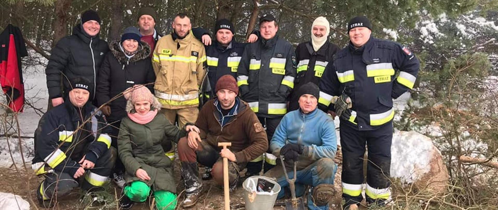 Zdjęcie zbiorowe - strażacy oraz inni uczestnicy poszukiwań w lesie na miejscu prowadzonych poszukiwań zaginionego szczeniaka