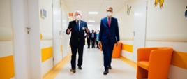 Premier Mateusz Morawiecki idzie wraz z dyrektorem placówki przez korytarz Centrum Chorób Rzadkich im. Fundacji Polsat.