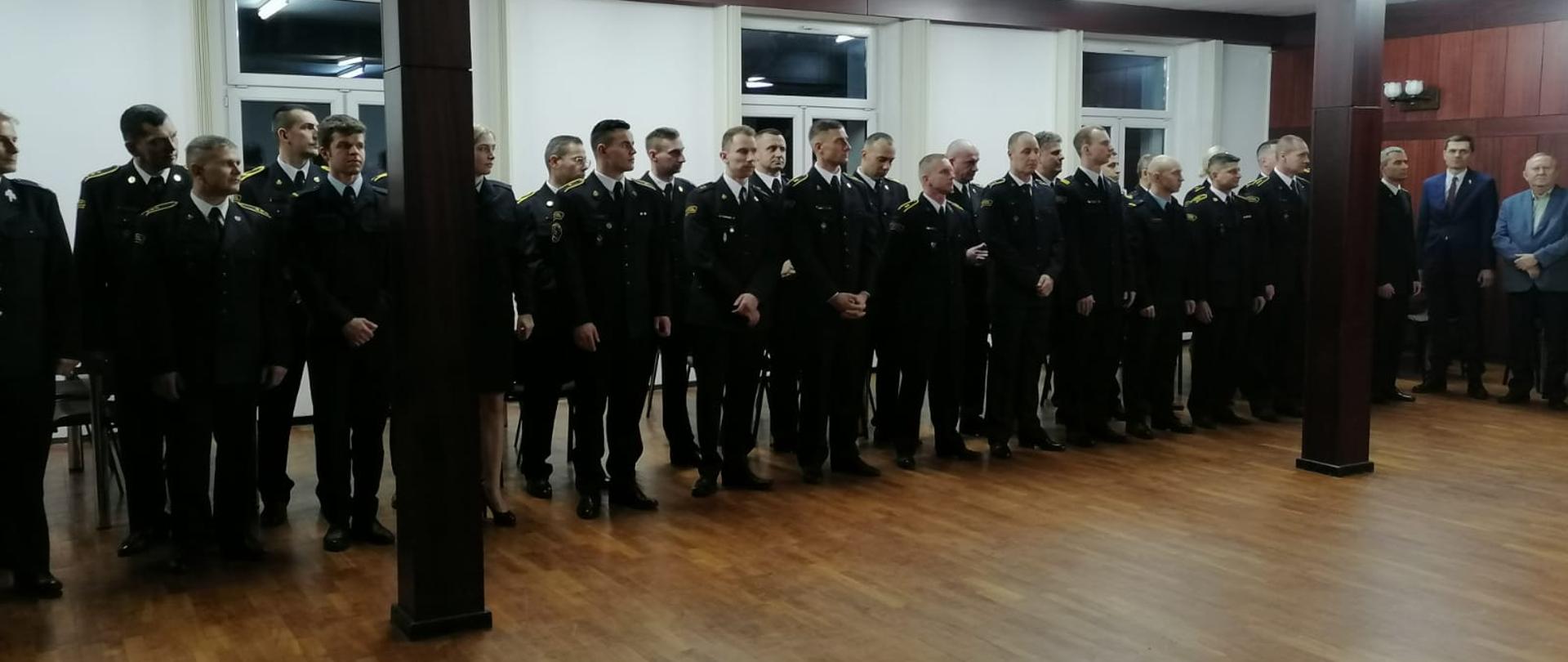 Uczestniczy spotkania stoją na sali podczas spotkania świątecznego.