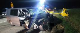 noc. autostrada, dwa rozbite pojazdy, w tle strażacy i wozy strażackie