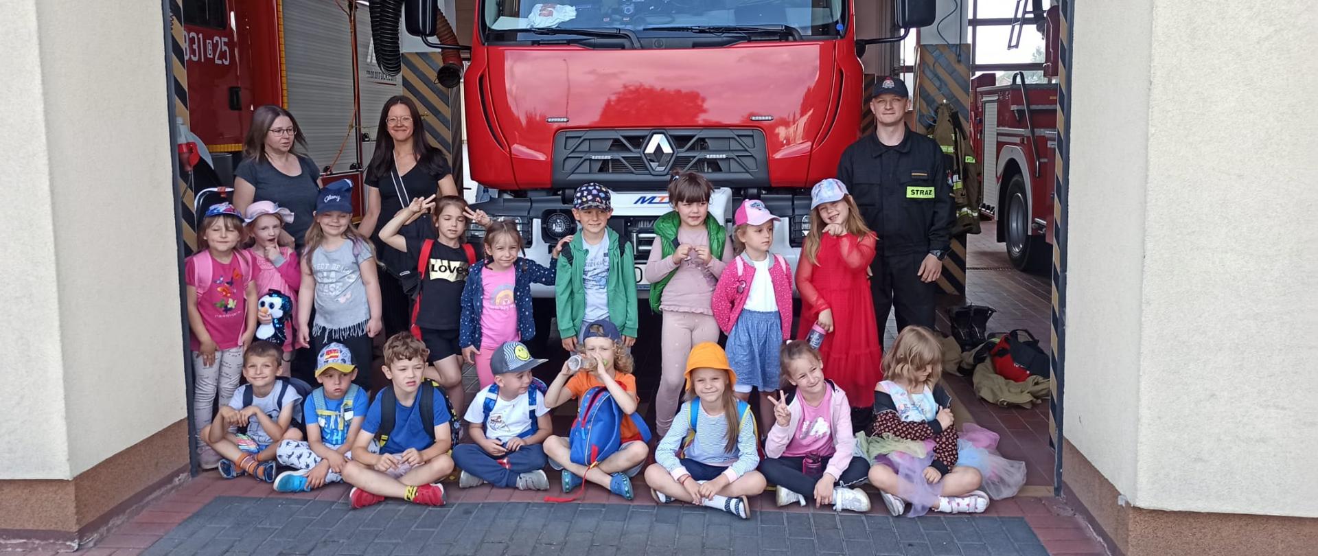 Dzieci znajdują się przed samochodem ratowniczo-gaśniczym i pozują do zdjęcia