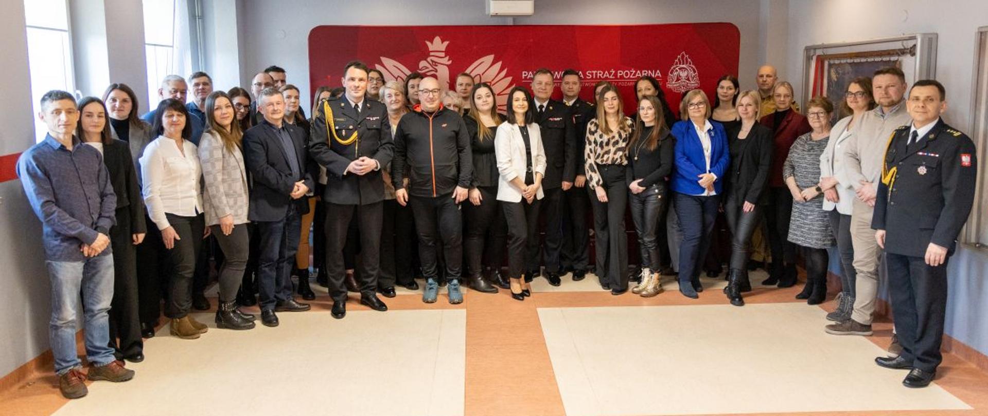 Wspólne zdjęcie uczestników uroczystego spotkania z okazji Dnia Służby Cywilnej. Zdjęcie wykonane w świetlicy Komendy Miejskiej PSP w Opolu.